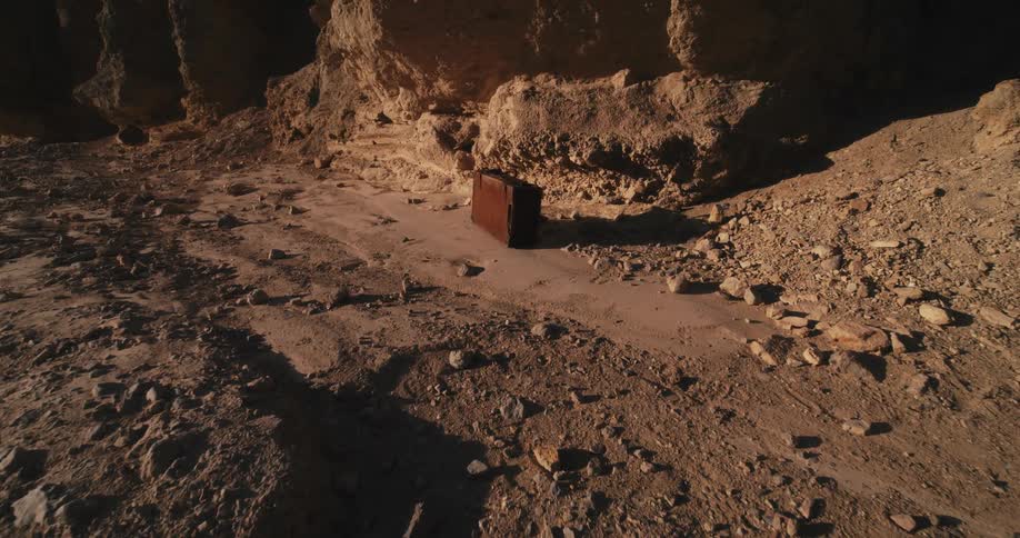 The sun shines on a briefcase sitting in the desert near a mountain