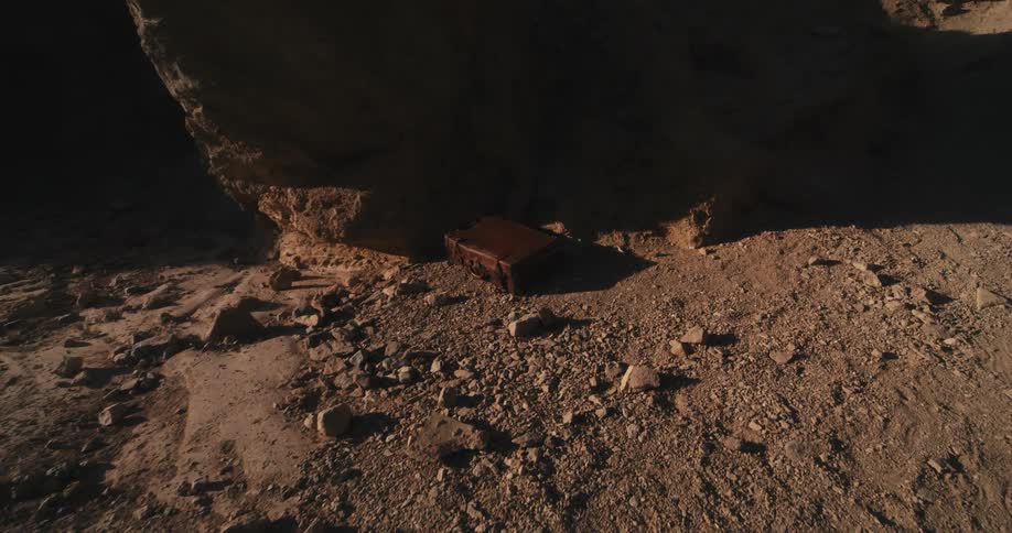 A small wooden box sits on the ground in a canyon
