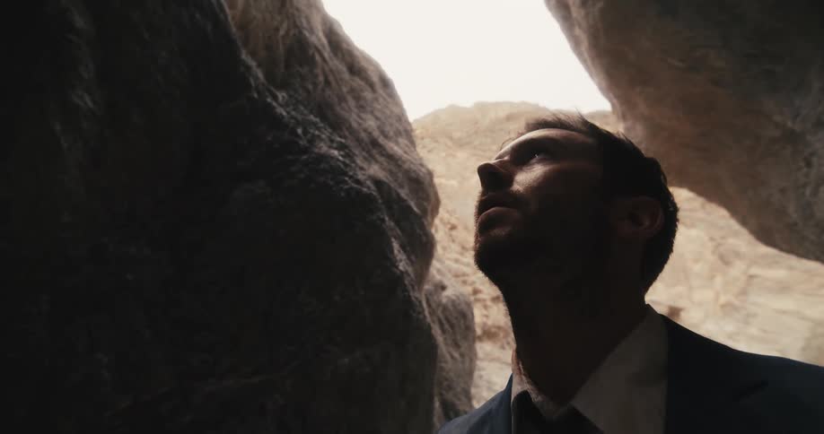 A man is standing outdoors near a cave during daytime