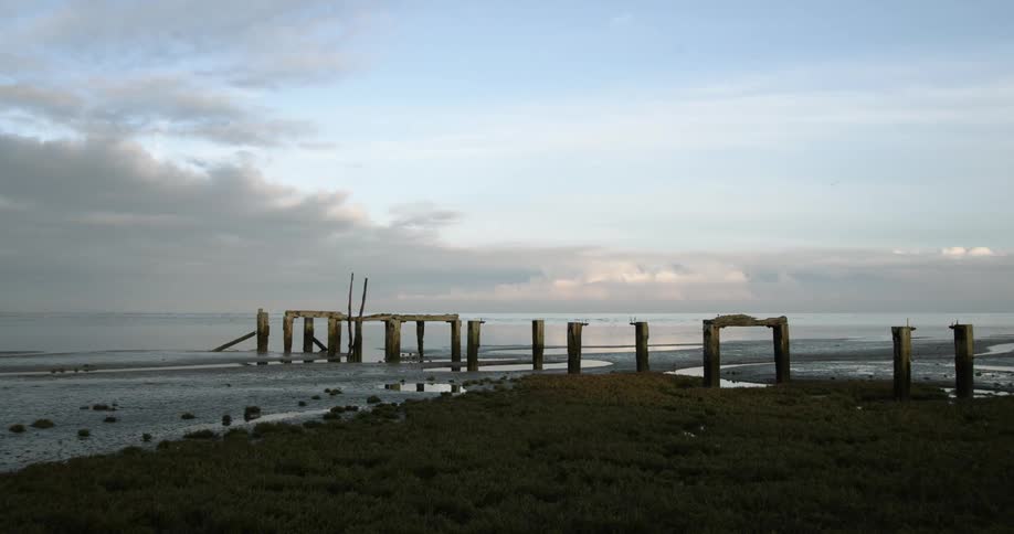A dilapidated pier on a beach during the day
