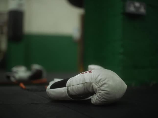 White boxing glove laying on black at the gym
