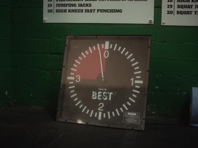Big analog chronometer reclined on the wall of a gym