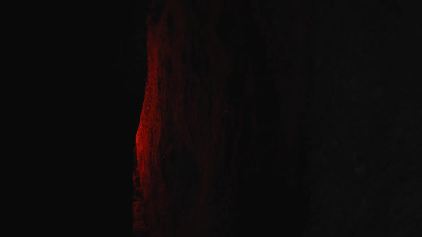 A red light glows in a tunnel in a cave