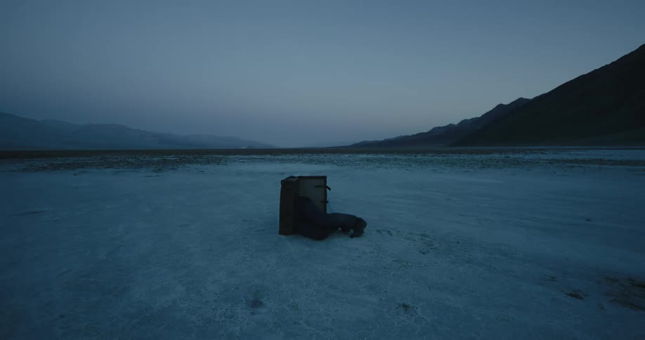 A man is crawling into a box on the ice