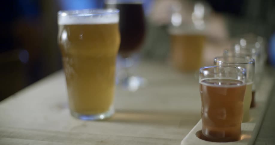 Beers in a variety of glasses sit on a bar top