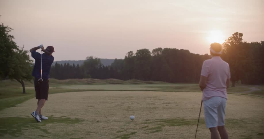 Two men play golf at sunset