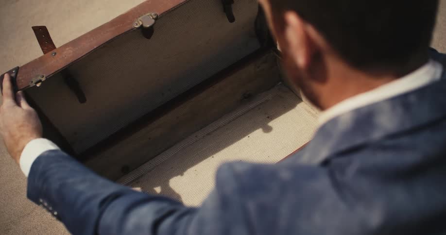 A man in the desert opens a briefcase and it is empty and he closes it