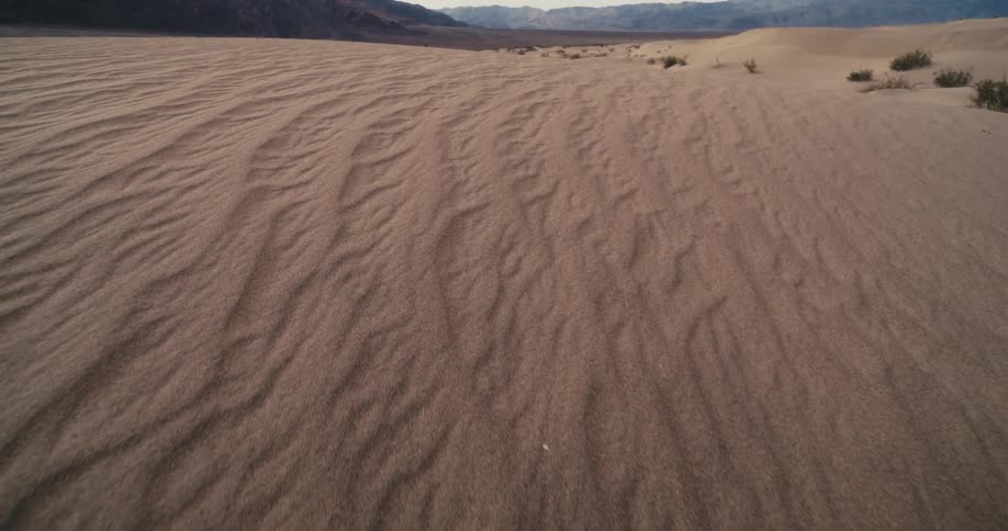 A sandy desert of rolling dunes surrounding by mountains