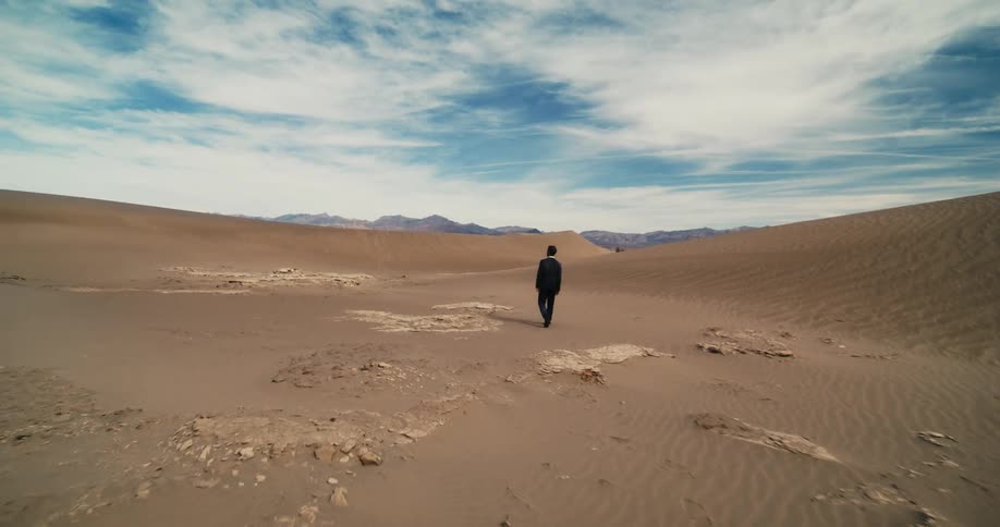 There is a man that is walking out onto the desert in the day time