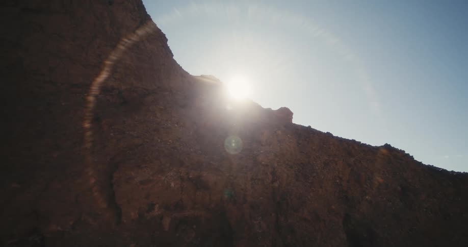 Sun hiding behind the rocky barren slopes of a mountain creates a halo