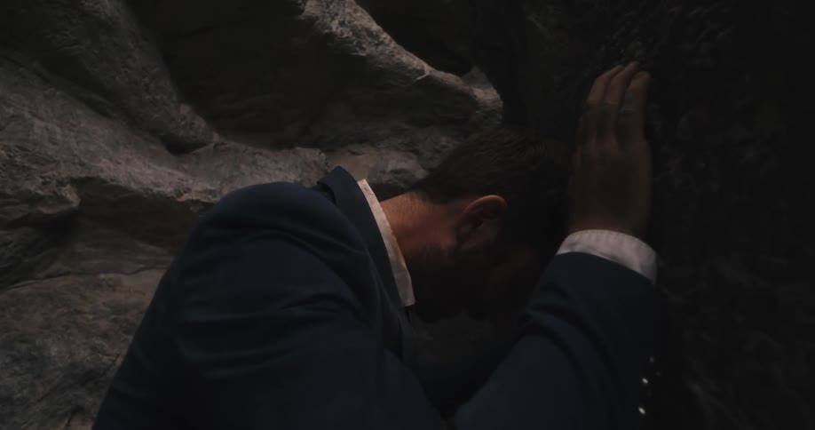 A man is stuck in a cave and looks upset