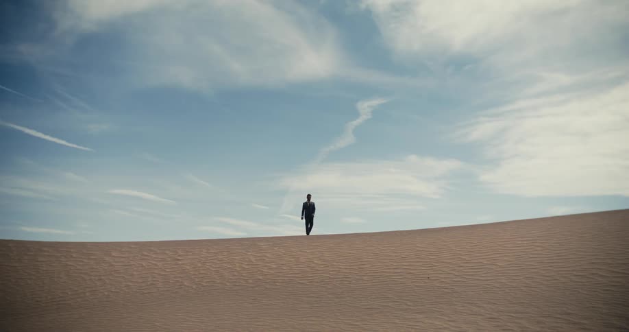 Man in dirty suit strive to walk in order to survive in the desert