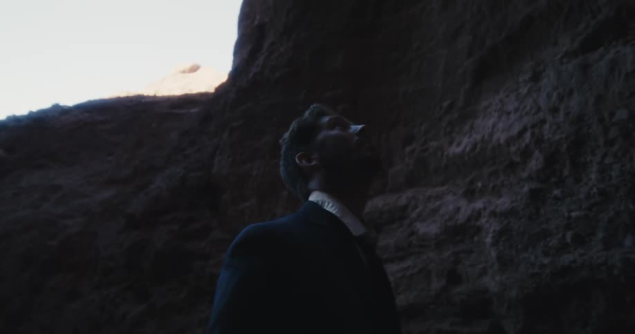 A sad man wearing a suit and tie is in a crevasse