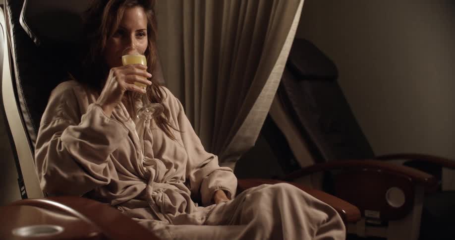 A woman sipping a mimosa laughs while sitting in a pedicure chair