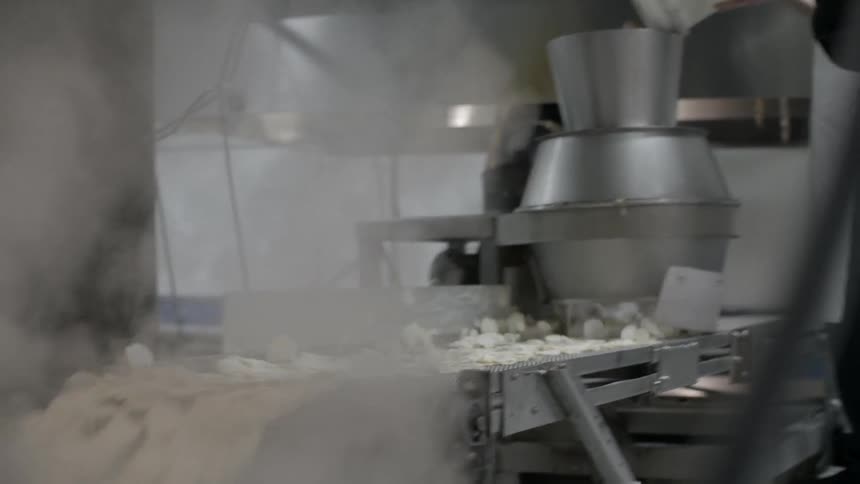 Potato chips pour off a conveyor belt into a vat
