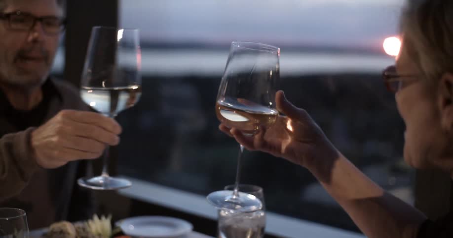 A man and woman cheers each other with wine at sunset
