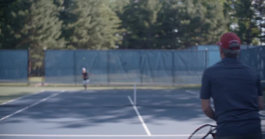 Two people playing tennis during the day
