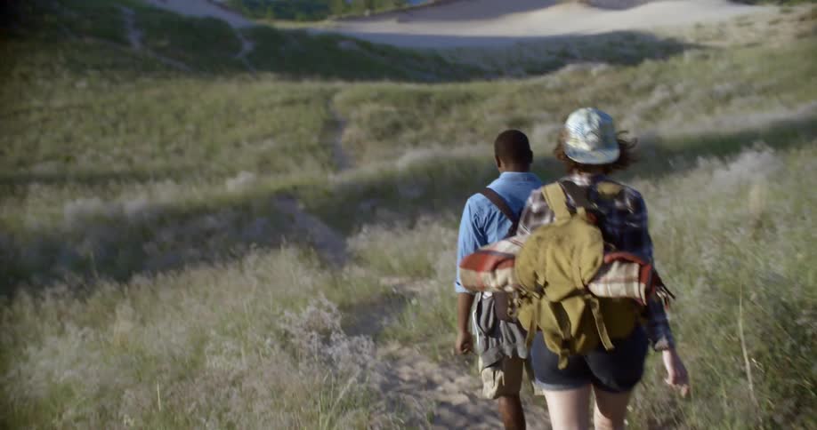 A man and woman hike down a path near a shoreline