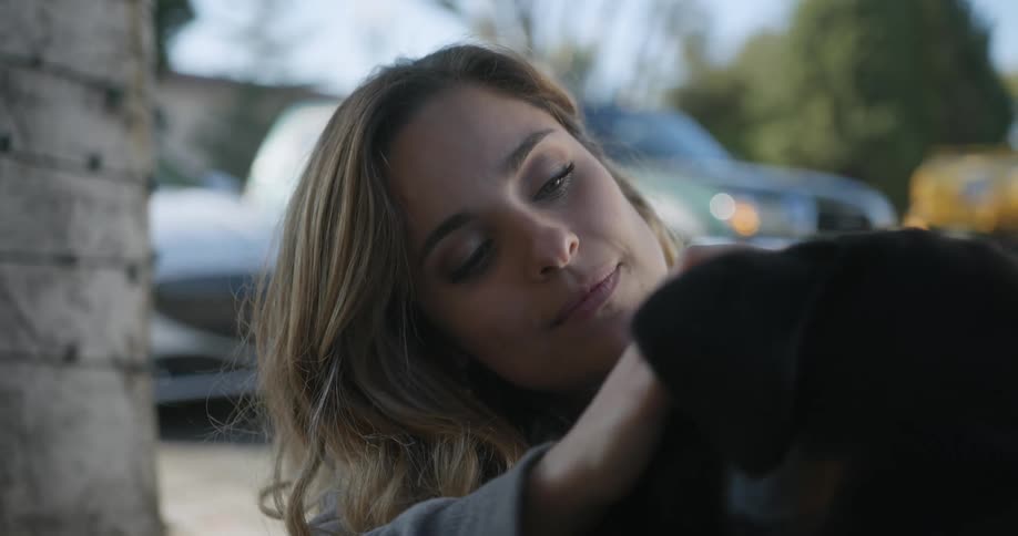 A woman hugs and pets a dog outdoors during the day