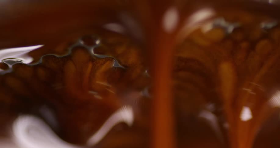 Chocolate liquid is rushing through small holes in a flat silver metal object
