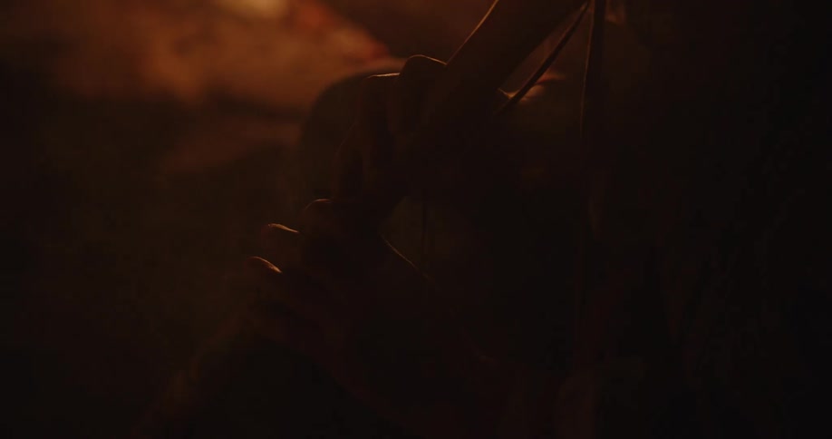 Silhouette of an african american shaman playing a wind instrument in front of a bonfire at night