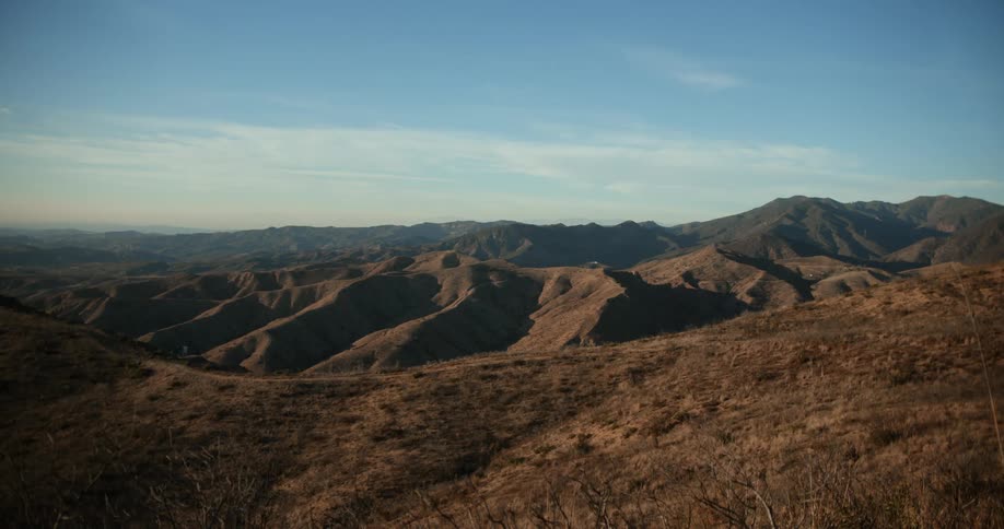 View from a mountain of mountains in the distance and on the horizon under a thin layer of clouds