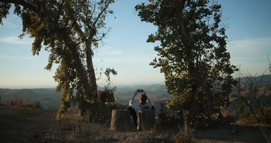 A person is taking pictures of the mountains from the cliff