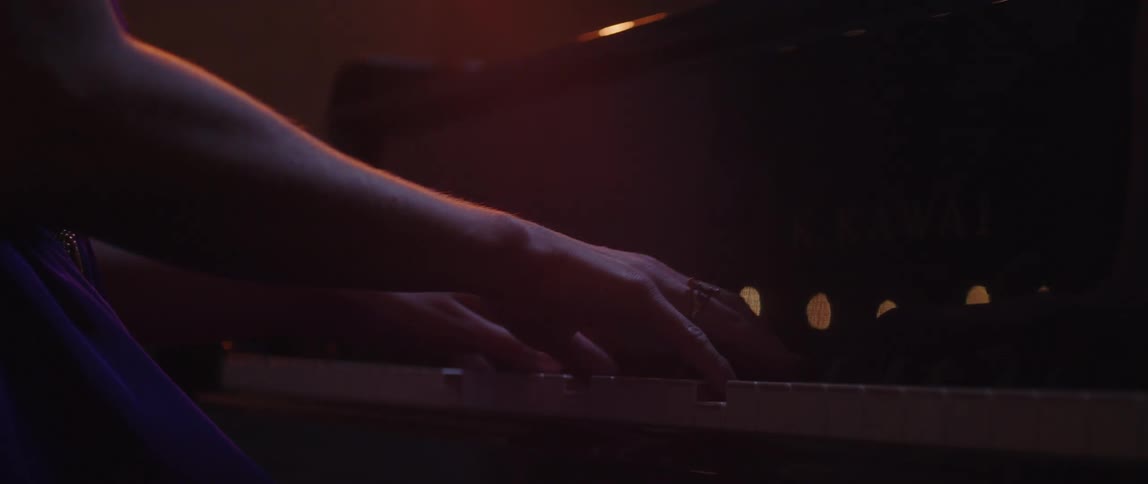 A woman plays the piano in a dark room