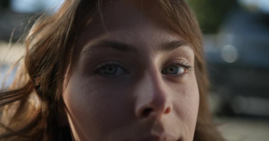 Woman with green eyes and brown hair looks at camera in front of cafe