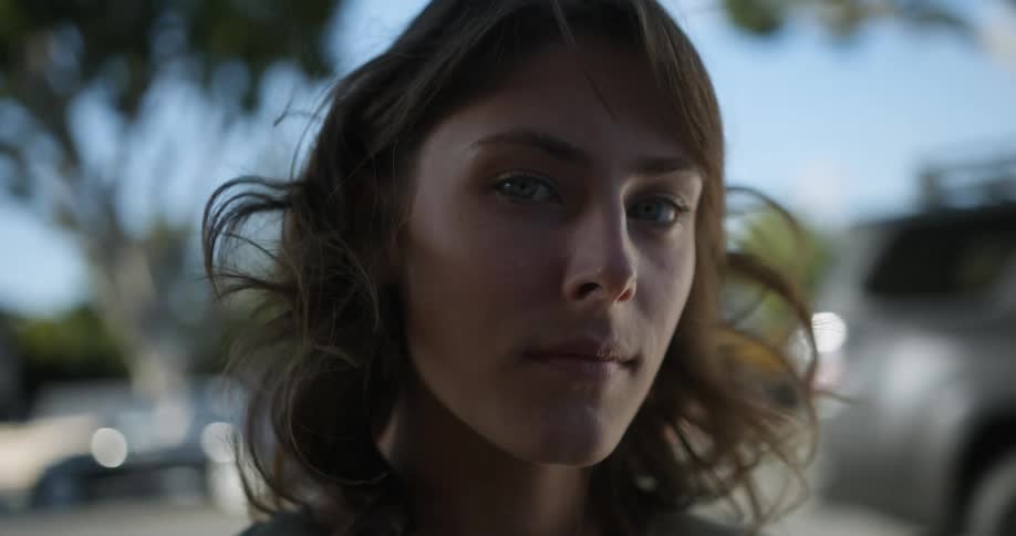 Close up of the face of a woman drinking a cup of coffe in the street looking at the camera