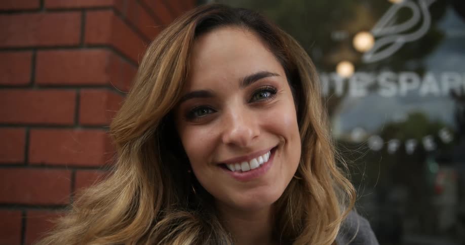 A woman smiles into the camera while outdoors during the day