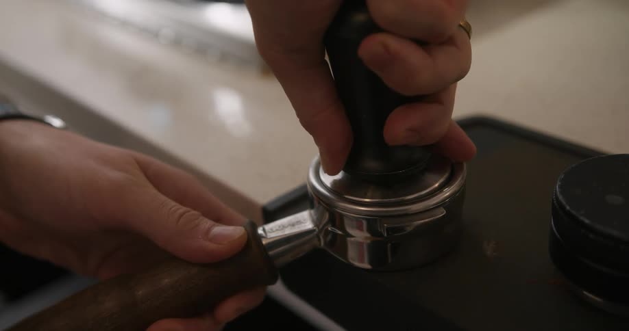 Person tamps coffee down while preparing to make coffee