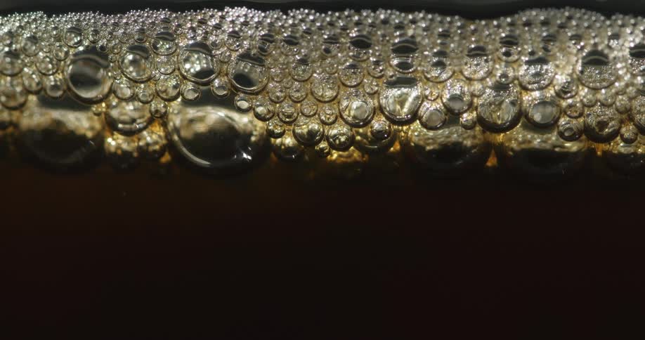 Bubbles of various size form foam on top of beverage