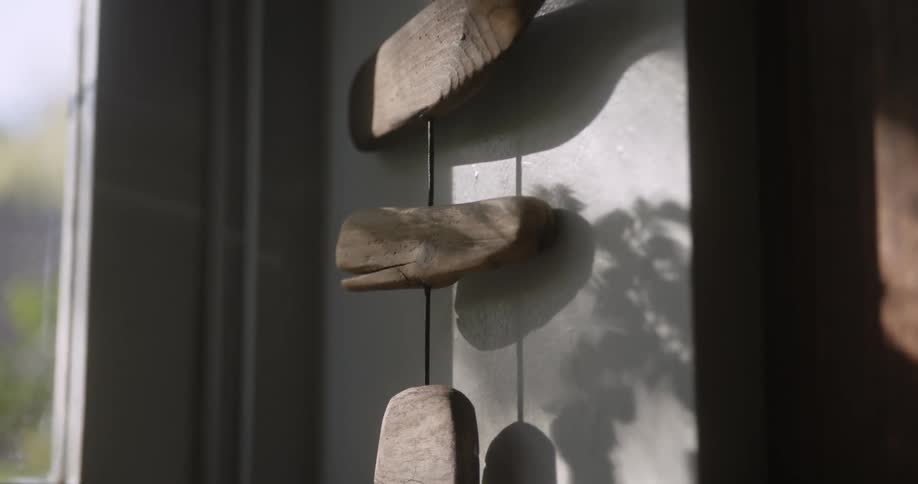 Close up of a hanging decoration made of wood pieces against a wall