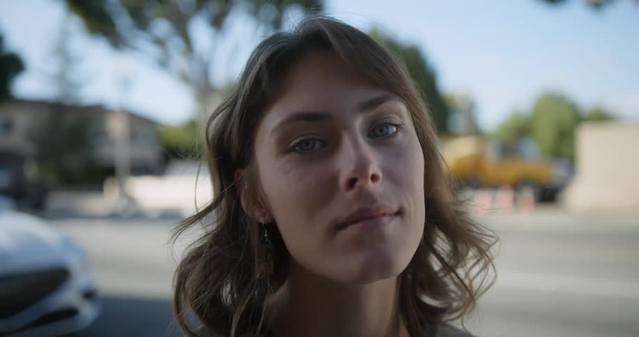 A woman is smiling by the moving cars
