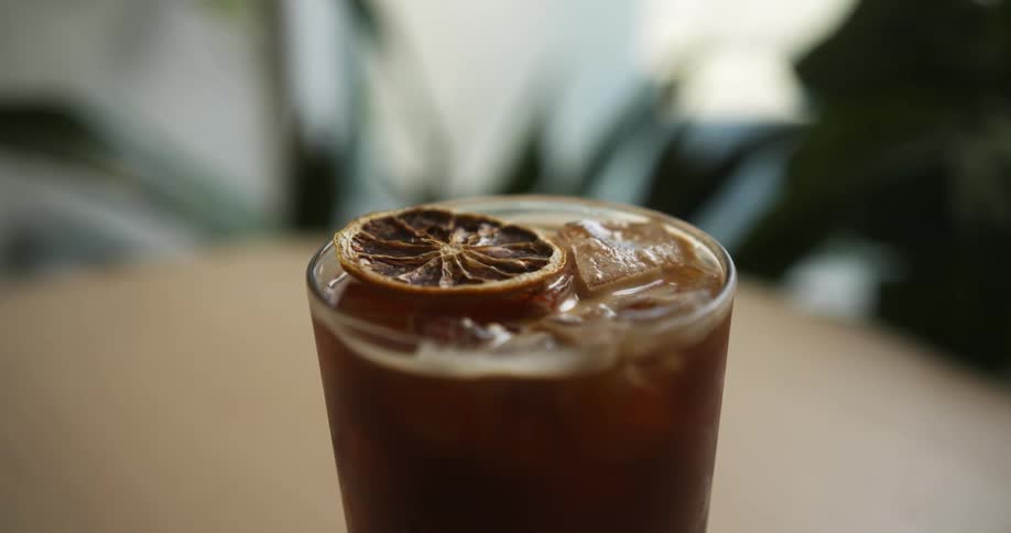 Close up cold brew coffee with ice cubes and lemon slice on table in cafe