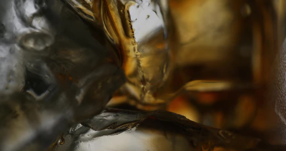 Dark amber liquid fills glass around ice cubes