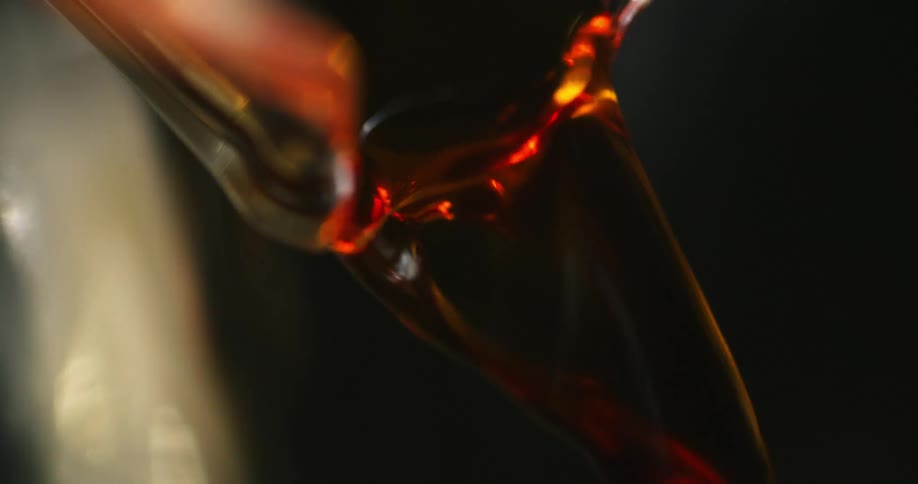 A red drink being poured from a glass container