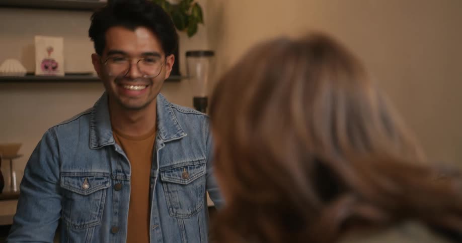 A smiling man looks up and speaks to the woman standing across from him
