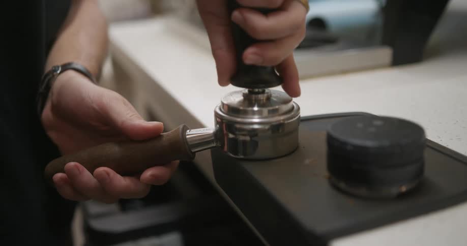 A woman is preparing coffee grounds for making coffee in a shop