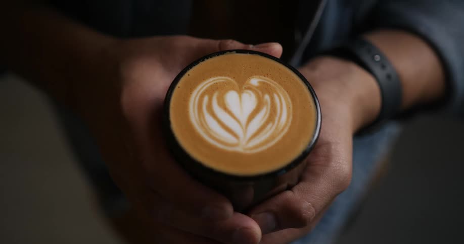 A man holds a hot beverage in his hands