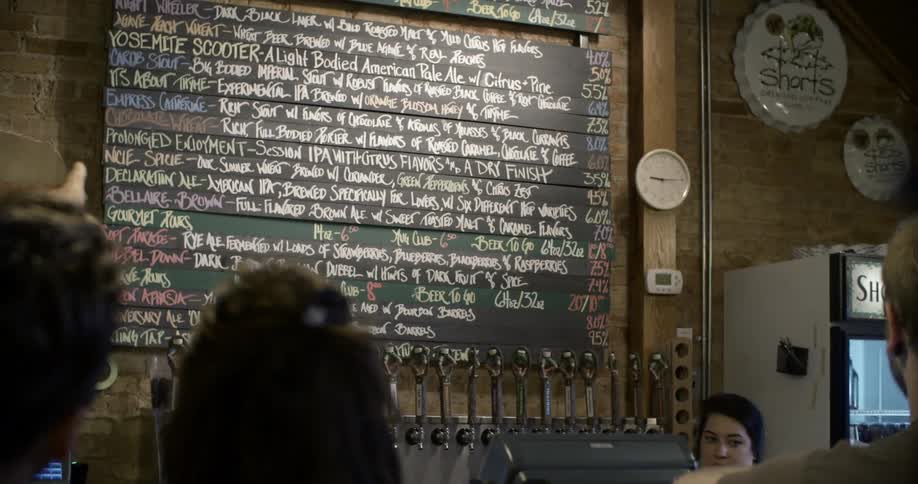 A man points to a restaurant menu on the wall