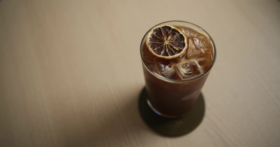 A man places a beverage on a tall glass over a coaster