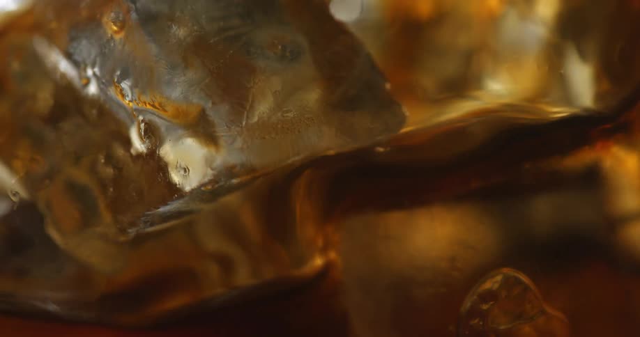Close up of coffee being poured into glass with ice cubes