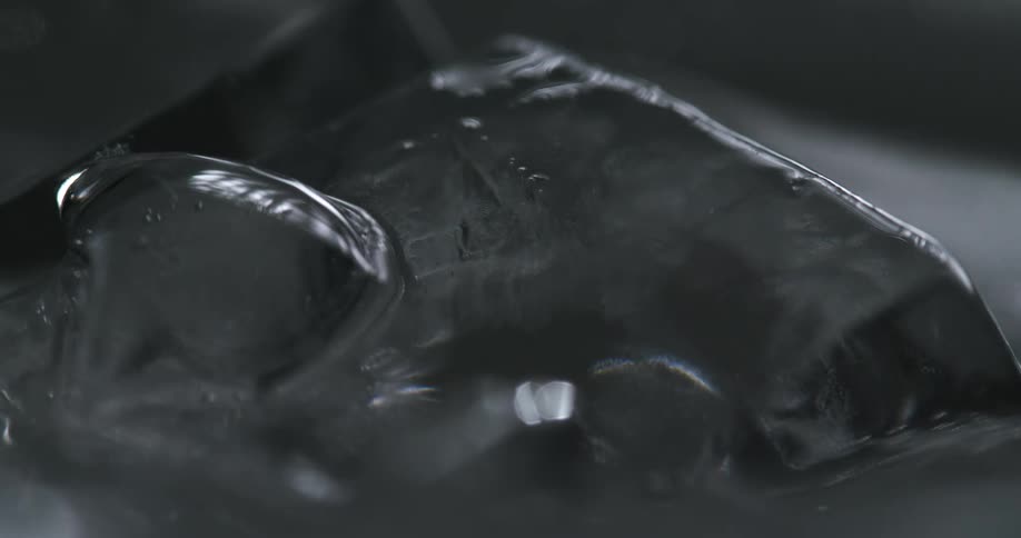 Close up of the surface of a glass filed with ice and sparkling water