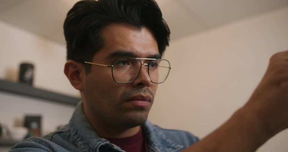 Barista with glasses and denim jacket works in coffee bar