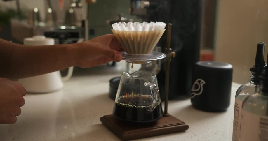 A person is brewing coffee in a pot