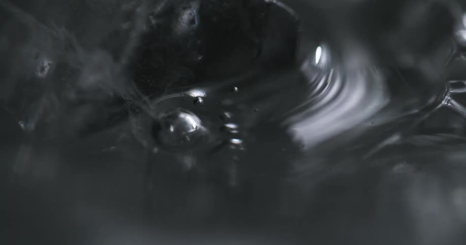 Close up of the surface of a glass filed with ice and sparkling water