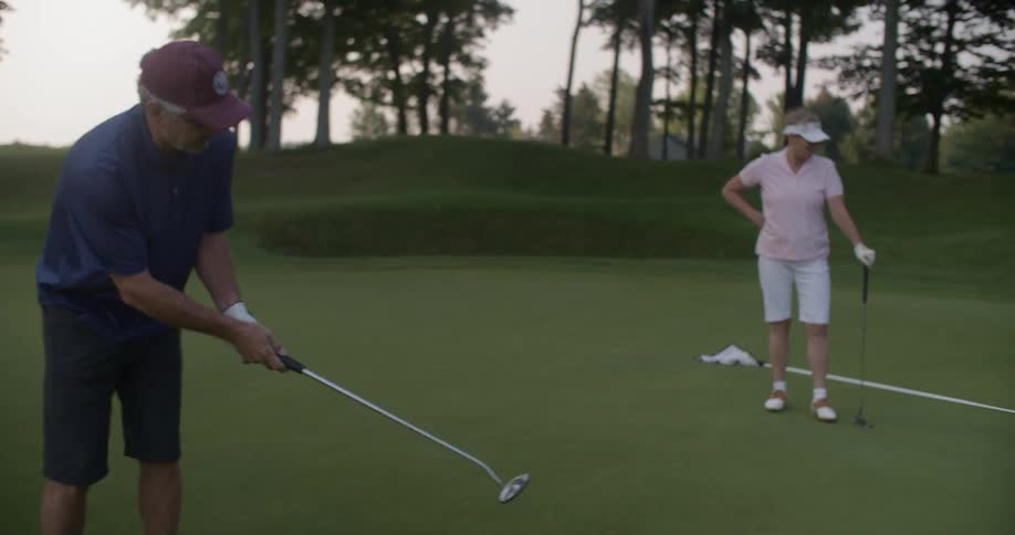 A man putts while his wife watches