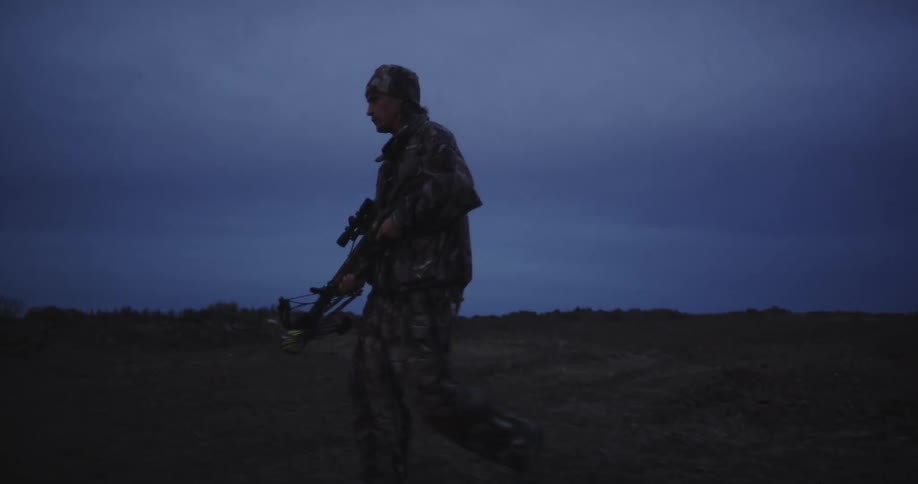 A hunter carrying a crossbow walks back to his pickup truck